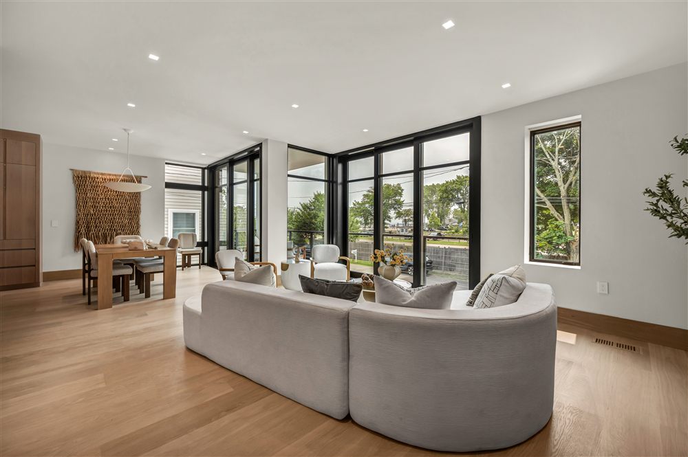 Modern living and dining area with a curved sofa and expansive black-framed windows