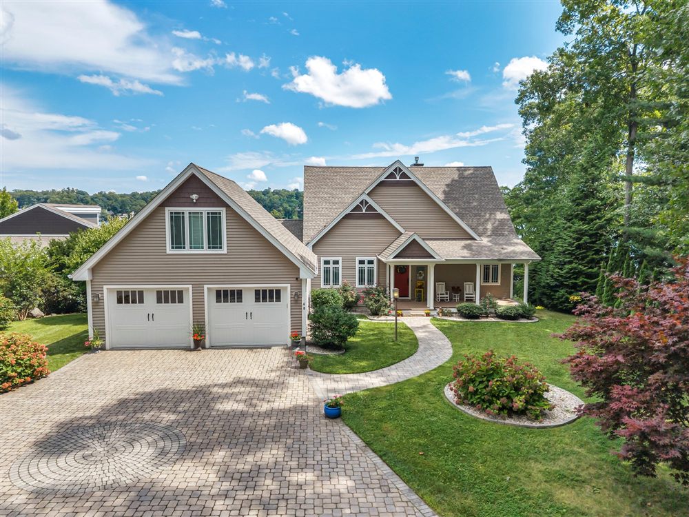 Elevated front view of a home with gabled rooflines, a landscaped lawn and a curved stone walkway